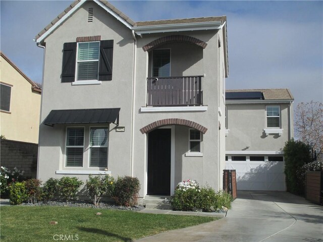 view of front of property featuring a front yard, a balcony, and a garage