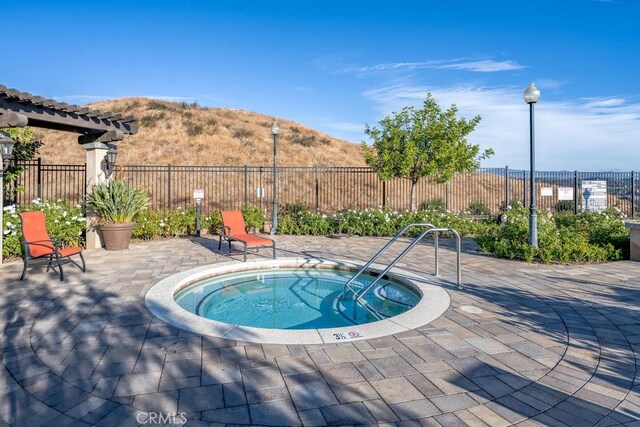 view of pool featuring a hot tub, a mountain view, and a patio area