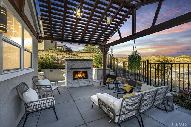 patio terrace at dusk featuring an outdoor living space with a fireplace and a pergola