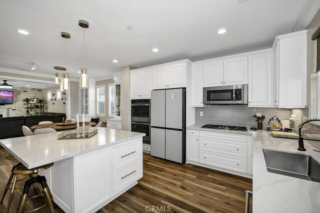 kitchen featuring a kitchen island, appliances with stainless steel finishes, sink, white cabinets, and hanging light fixtures