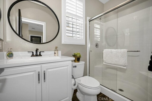 bathroom with walk in shower, vanity, and toilet