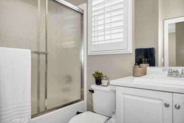 full bathroom featuring vanity, shower / bath combination with glass door, and toilet