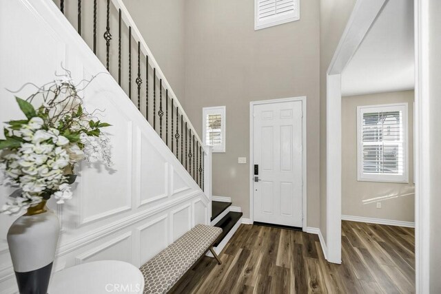 foyer entrance featuring dark wood-type flooring and a towering ceiling