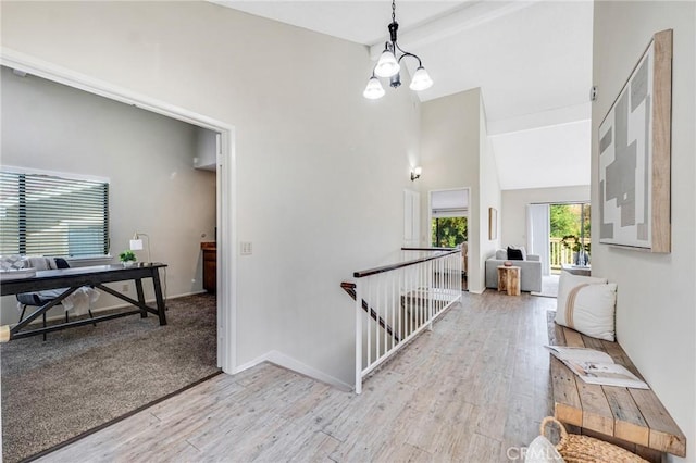 hallway featuring light hardwood / wood-style floors, a notable chandelier, and vaulted ceiling