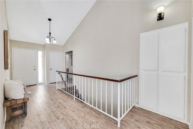 foyer entrance with an inviting chandelier, hardwood / wood-style floors, and high vaulted ceiling