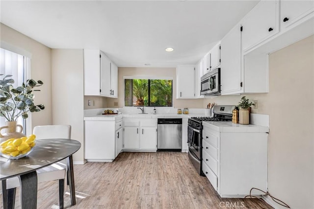 kitchen with white cabinets, light wood-type flooring, and stainless steel appliances