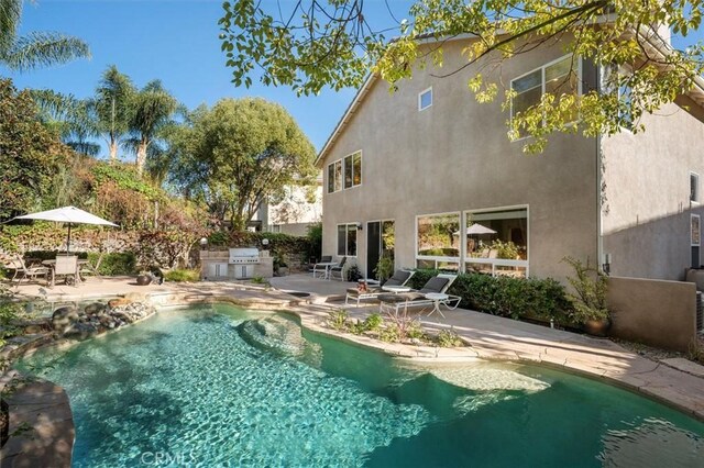 view of pool featuring exterior kitchen, a grill, and a patio