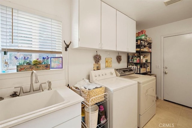 laundry room featuring washing machine and dryer, sink, cabinets, and light tile patterned floors