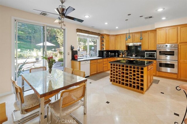 kitchen featuring ceiling fan, appliances with stainless steel finishes, tasteful backsplash, a kitchen island, and pendant lighting