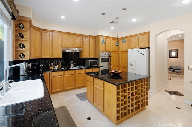 kitchen with appliances with stainless steel finishes, backsplash, hanging light fixtures, a kitchen island, and sink