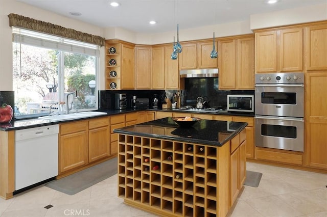 kitchen featuring appliances with stainless steel finishes, decorative backsplash, dark stone countertops, a kitchen island, and sink