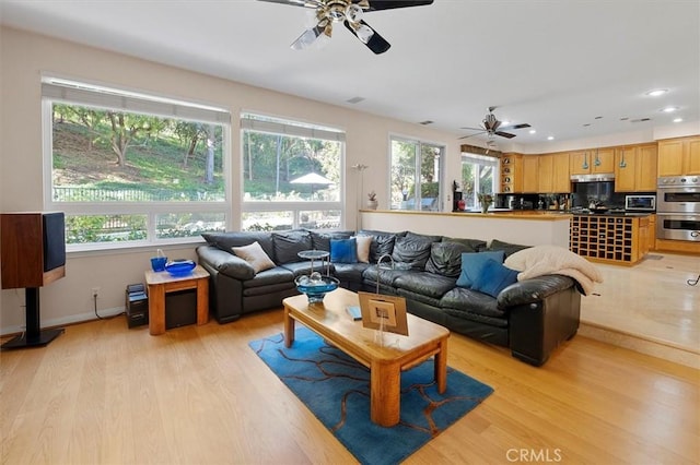 living room with ceiling fan, light hardwood / wood-style flooring, and a wealth of natural light