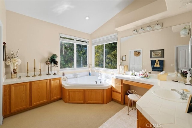 bathroom with a bathtub, vanity, and vaulted ceiling