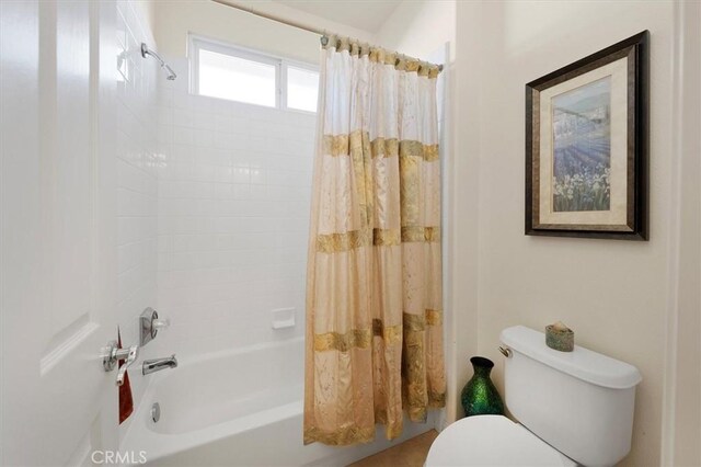 bathroom featuring toilet and shower / bath combination with curtain