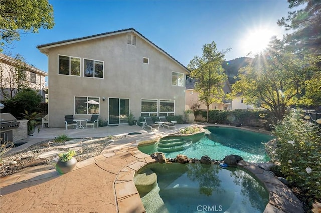 rear view of house with a patio area, an outdoor kitchen, and a swimming pool with hot tub