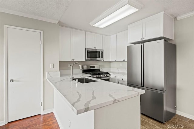 kitchen with light stone countertops, appliances with stainless steel finishes, white cabinets, and kitchen peninsula