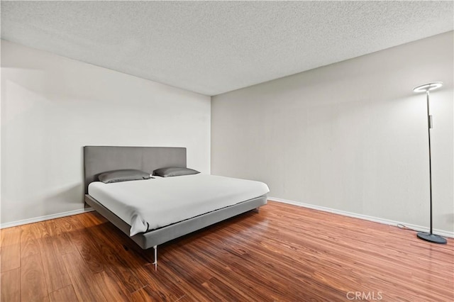 bedroom featuring wood-type flooring and a textured ceiling