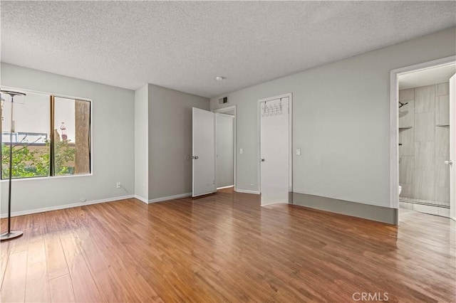 unfurnished bedroom with a baseboard radiator, wood-type flooring, and a textured ceiling