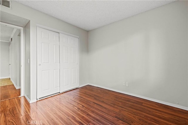 unfurnished bedroom with hardwood / wood-style flooring, a textured ceiling, and a closet