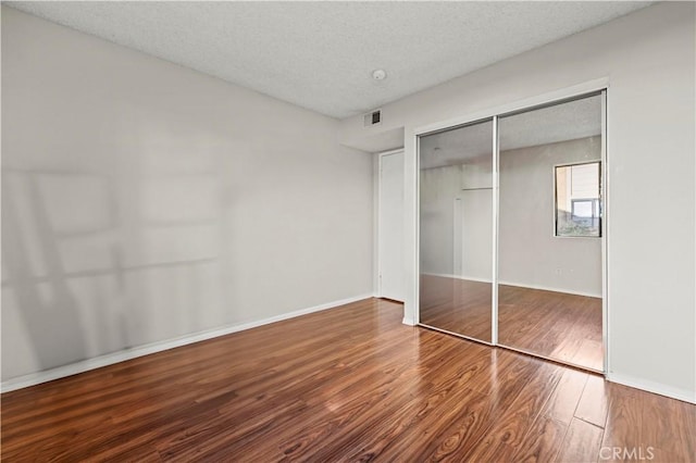 unfurnished bedroom with wood-type flooring, a closet, and a textured ceiling