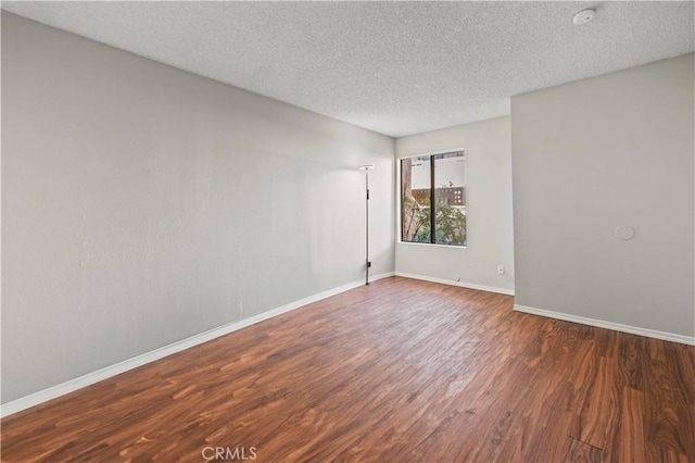 unfurnished room featuring a textured ceiling and dark hardwood / wood-style flooring