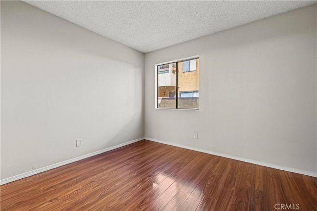 unfurnished room with hardwood / wood-style flooring and a textured ceiling