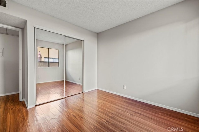 unfurnished bedroom featuring hardwood / wood-style floors, a closet, and a textured ceiling