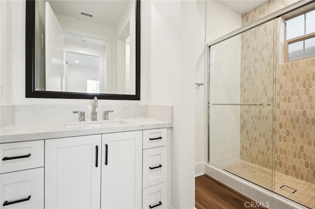 bathroom featuring a shower with shower door, hardwood / wood-style flooring, and vanity