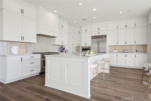 kitchen featuring white cabinets, high quality appliances, and a center island with sink