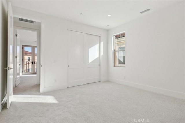 unfurnished bedroom with light colored carpet and a closet