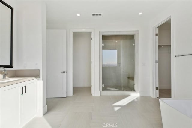 bathroom with a shower with door, vanity, and tile patterned flooring