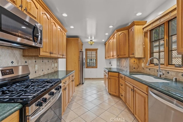 kitchen featuring tasteful backsplash, dark stone countertops, sink, stainless steel appliances, and light tile patterned floors