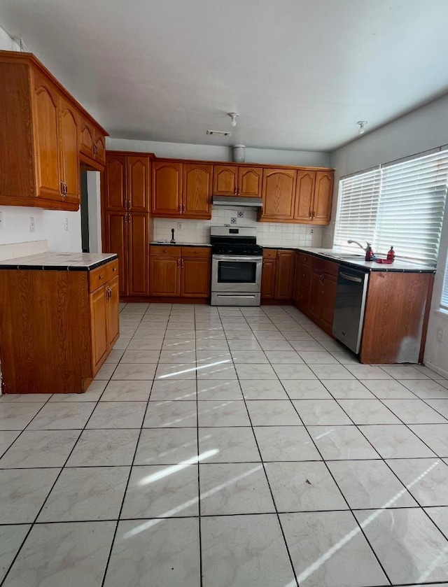 kitchen featuring light tile patterned floors, stainless steel appliances, and decorative backsplash