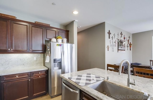 kitchen featuring light stone countertops, sink, light hardwood / wood-style flooring, and stainless steel appliances