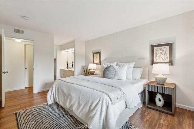 bedroom with hardwood / wood-style flooring and connected bathroom