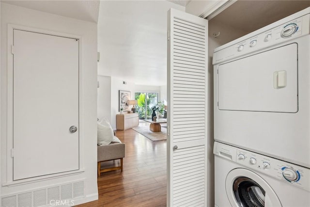 laundry area featuring stacked washing maching and dryer and hardwood / wood-style floors