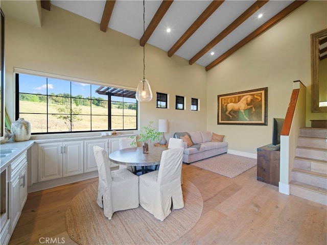 dining room with high vaulted ceiling, beamed ceiling, and light hardwood / wood-style floors