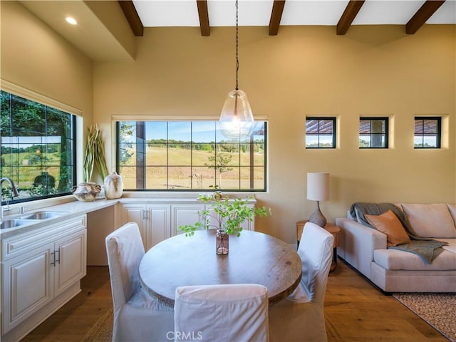 dining space featuring dark wood-type flooring, sink, and beam ceiling