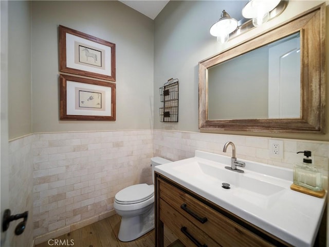 bathroom featuring hardwood / wood-style flooring, tile walls, toilet, and vanity