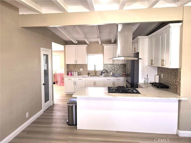 kitchen featuring black gas stovetop, extractor fan, white cabinetry, a kitchen breakfast bar, and kitchen peninsula