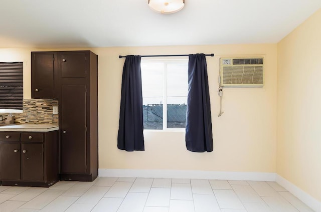 kitchen with decorative backsplash, dark brown cabinetry, and a wall mounted air conditioner