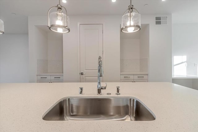 kitchen with light stone countertops, decorative light fixtures, and sink