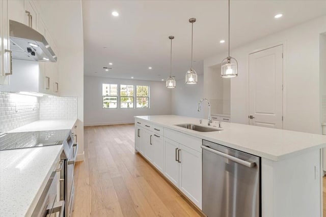 kitchen featuring an island with sink, pendant lighting, stainless steel dishwasher, white cabinets, and sink