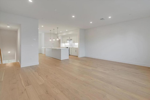 unfurnished living room featuring sink and light hardwood / wood-style floors