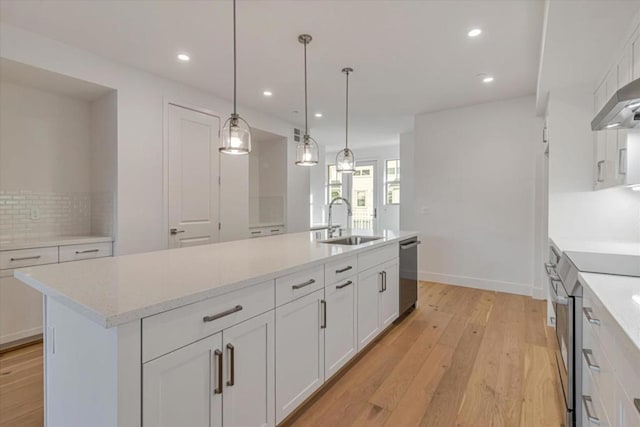 kitchen featuring sink, white cabinets, appliances with stainless steel finishes, and an island with sink