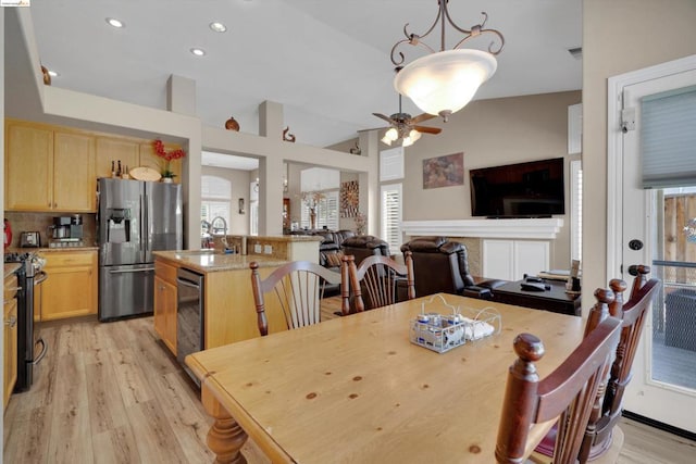 dining space with light hardwood / wood-style floors, sink, lofted ceiling, and ceiling fan