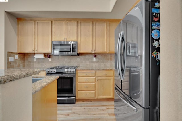 kitchen featuring tasteful backsplash, light hardwood / wood-style floors, light stone countertops, appliances with stainless steel finishes, and light brown cabinets