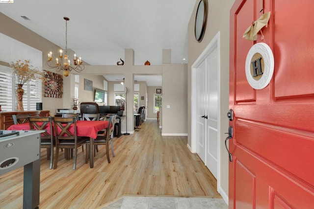 entryway featuring ceiling fan with notable chandelier and light hardwood / wood-style flooring