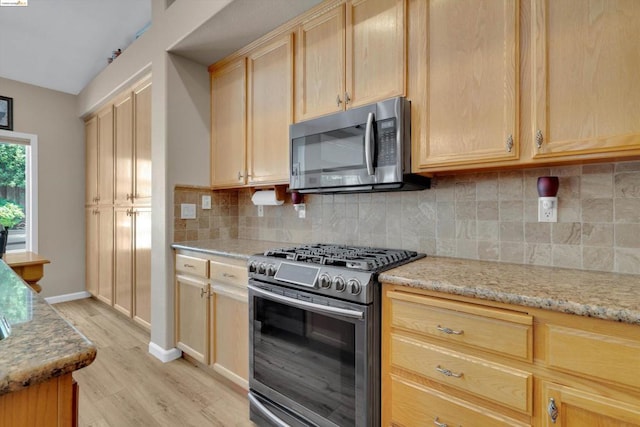 kitchen featuring backsplash, light hardwood / wood-style flooring, light stone countertops, appliances with stainless steel finishes, and light brown cabinetry