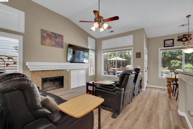 living room with light hardwood / wood-style floors, lofted ceiling, ceiling fan, and a fireplace